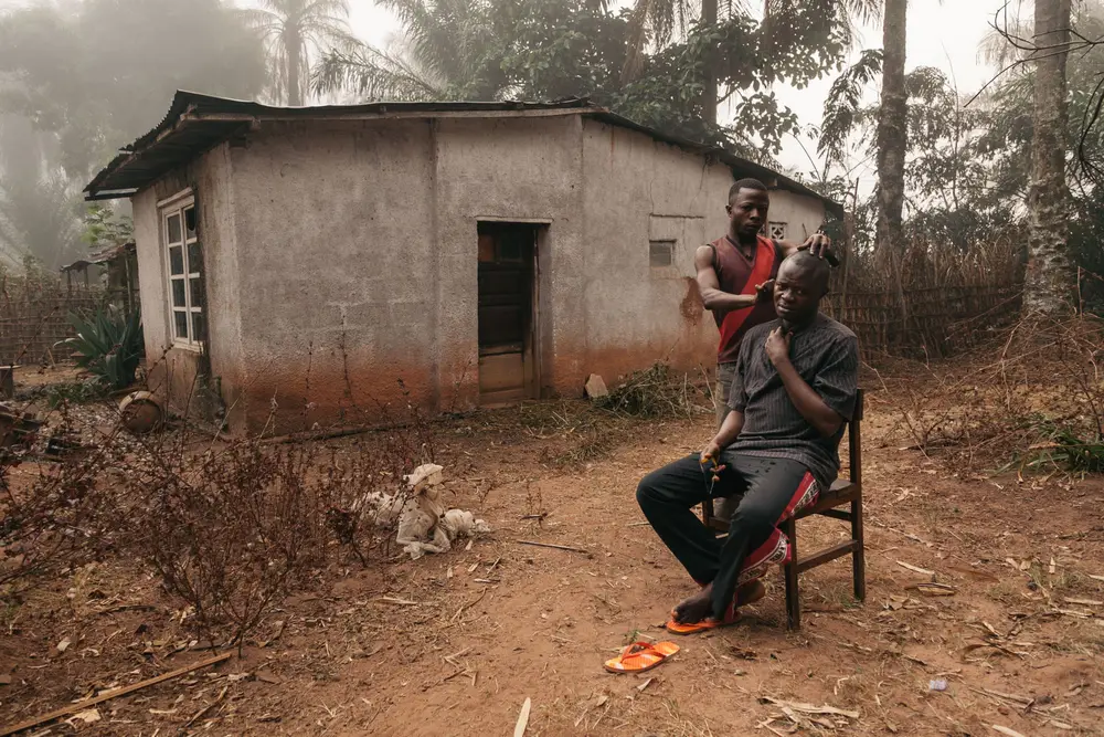 After leaving the pirogue to a village on the river we struggled on by bicycle to the Bilomba Catholic mission. One of the brothers shaves the head of an elder father in the courtyard.