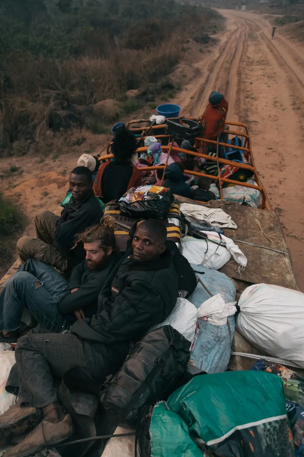 Resting in the early hours of the morning while waiting for repairs to the truck. With no seats everybody simply holds on to their neighbour and braces themselves for the bumpy ride and the impact of low tree branches.